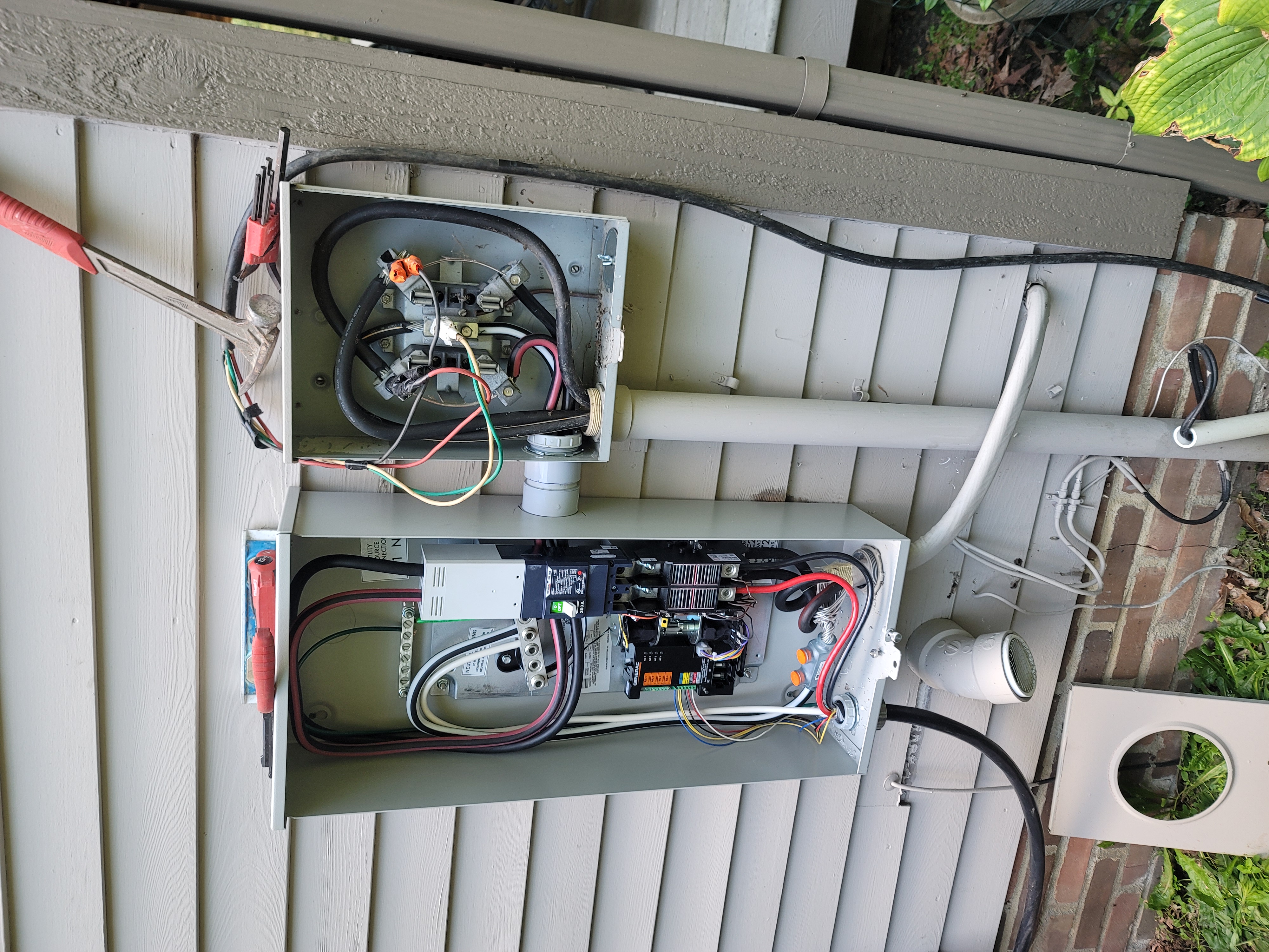 Electrical circuit breaker panel installed in a wall, showing various wires and breakers