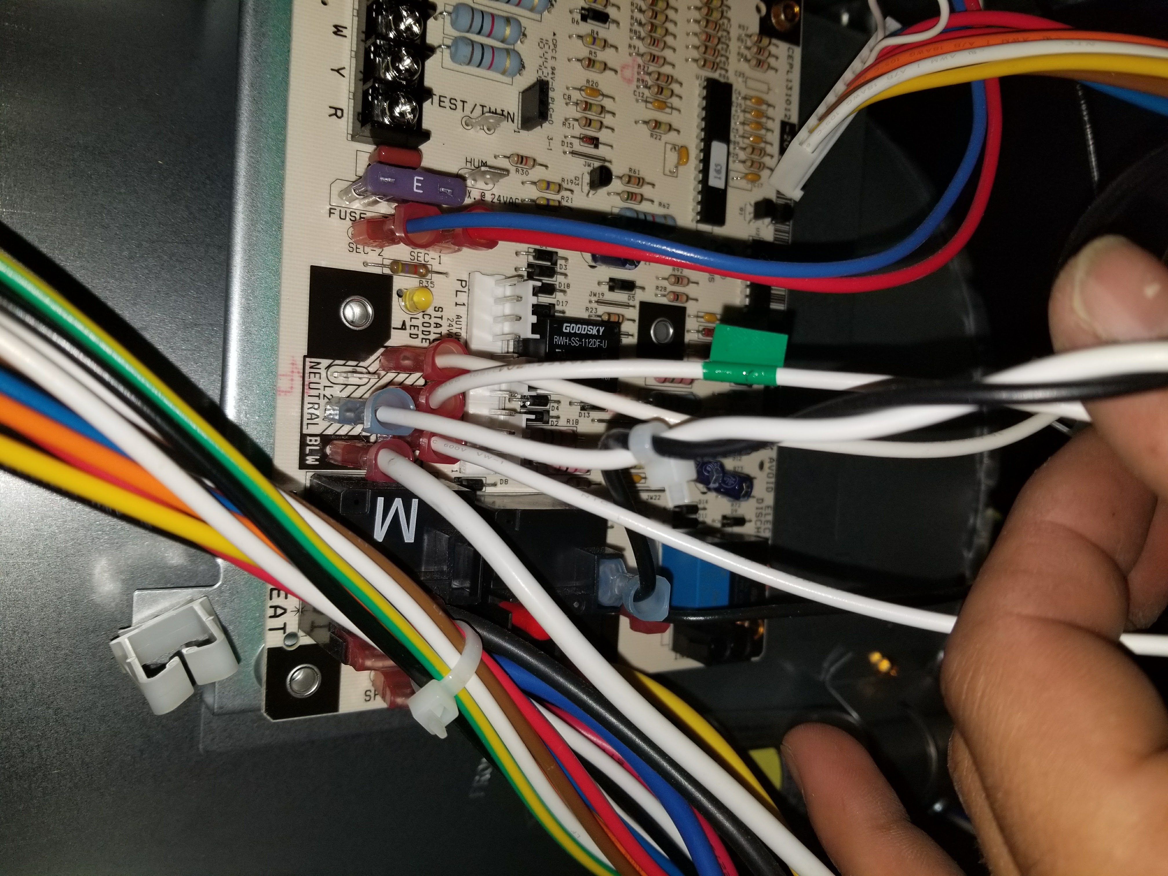 Hands using wire stripper to remove insulation from a wire inside a wall box