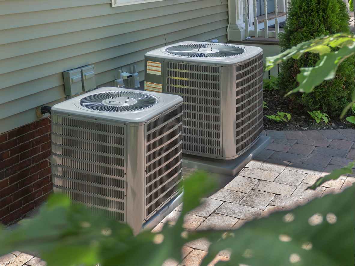 Gray air conditioning units lined up outside a building