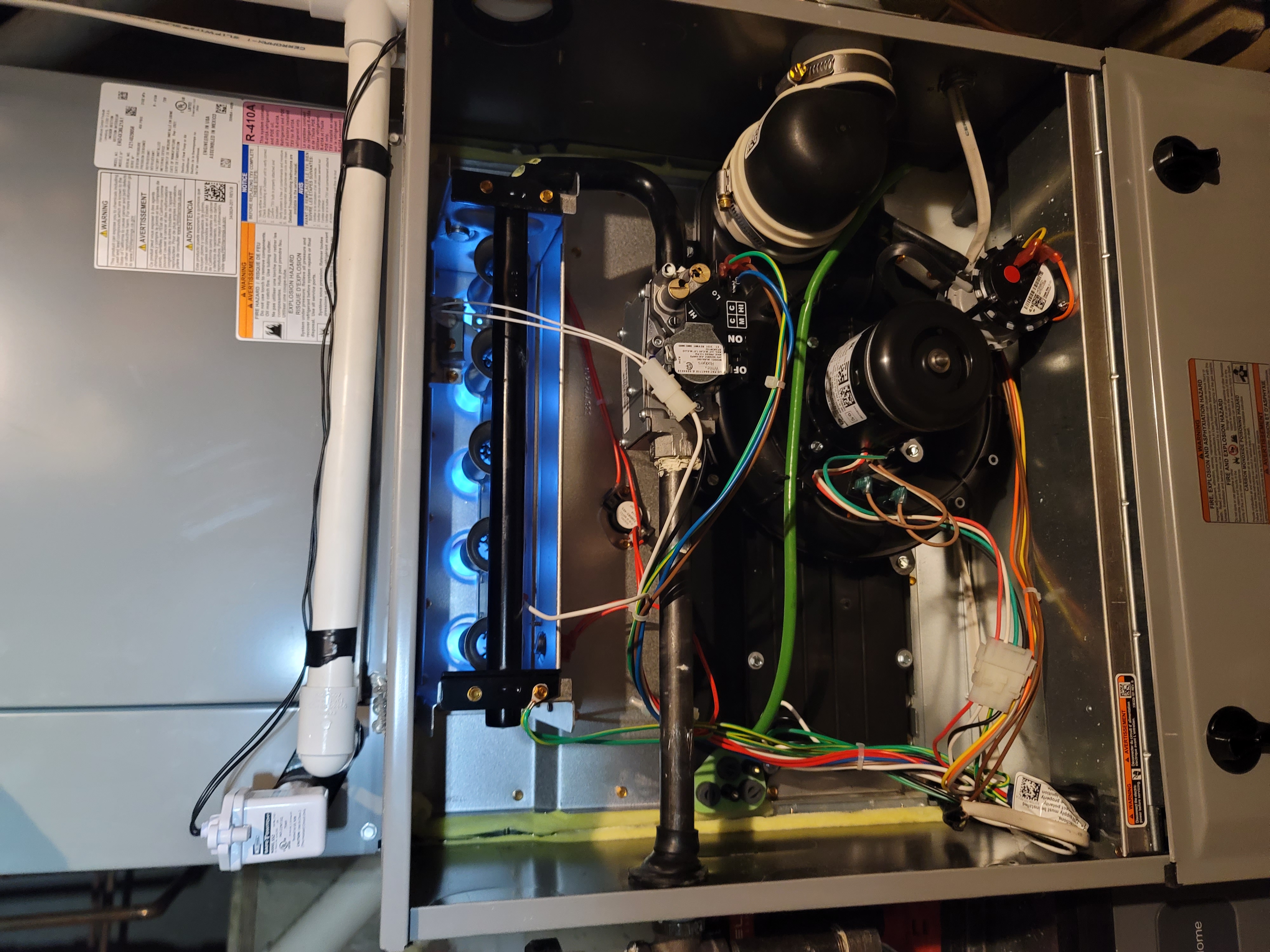 Gas furnace with blue flames, open, showing internal components and wiring