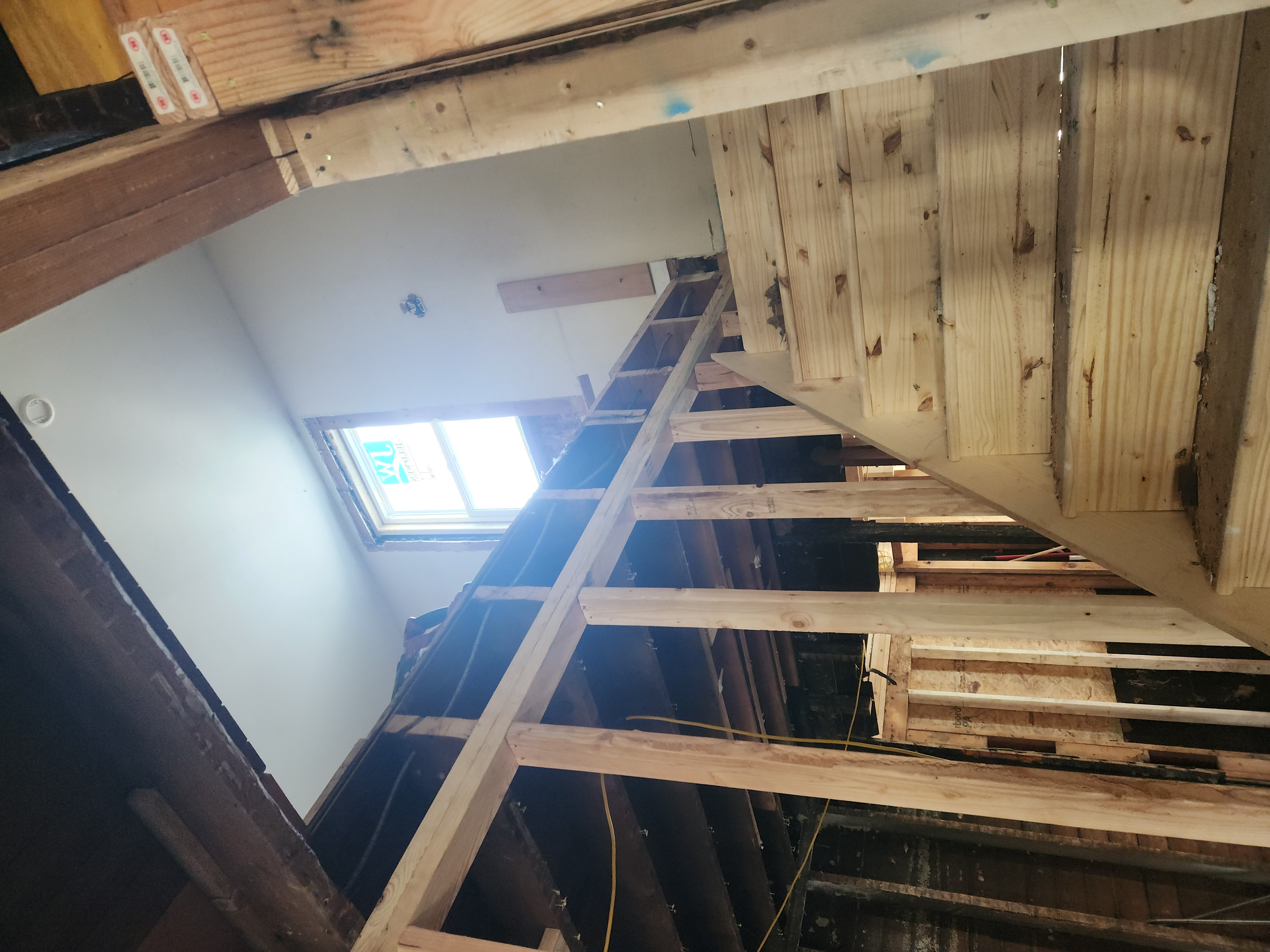 Kitchen partially framed during renovation with finished white cabinets, island, and granite countertops