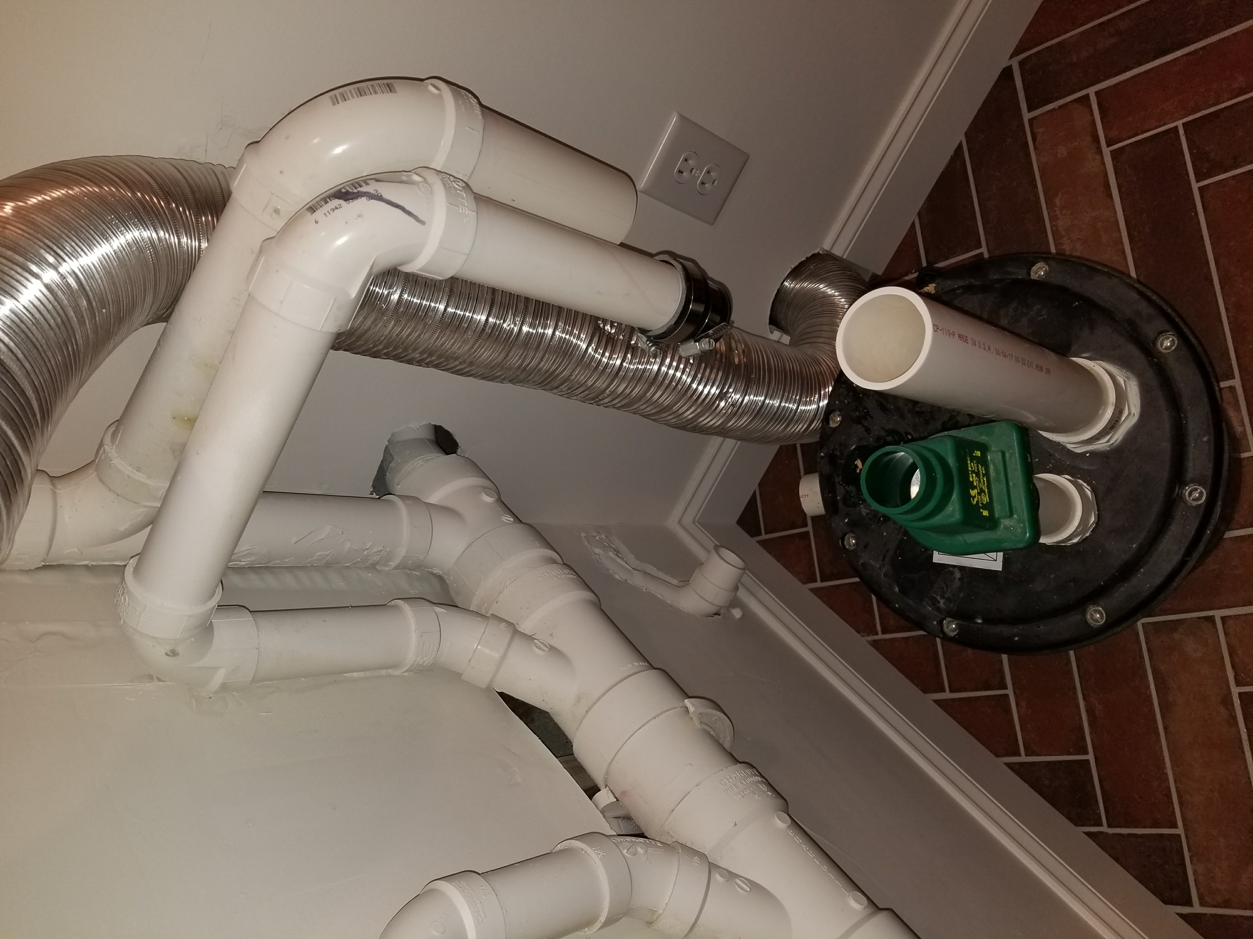 Sump pump system in a basement corner: black pump, white pipes, blue pipe, green valves
