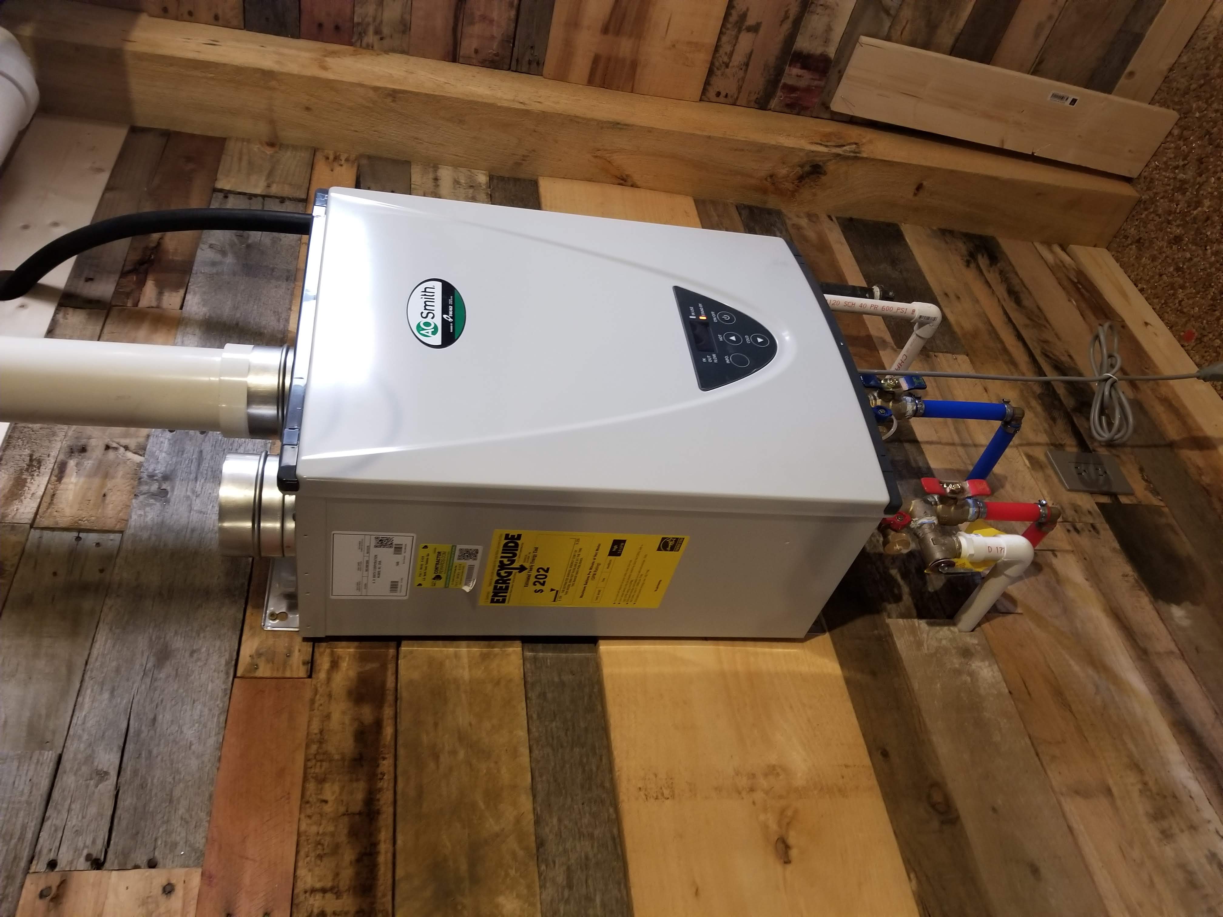 White tankless water heater mounted on a wood-paneled wall